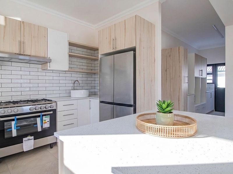 Modern kitchen featuring light wood cabinetry, stone countertops, a central island, subway tile backsplash, and a stainless steel gas stove.