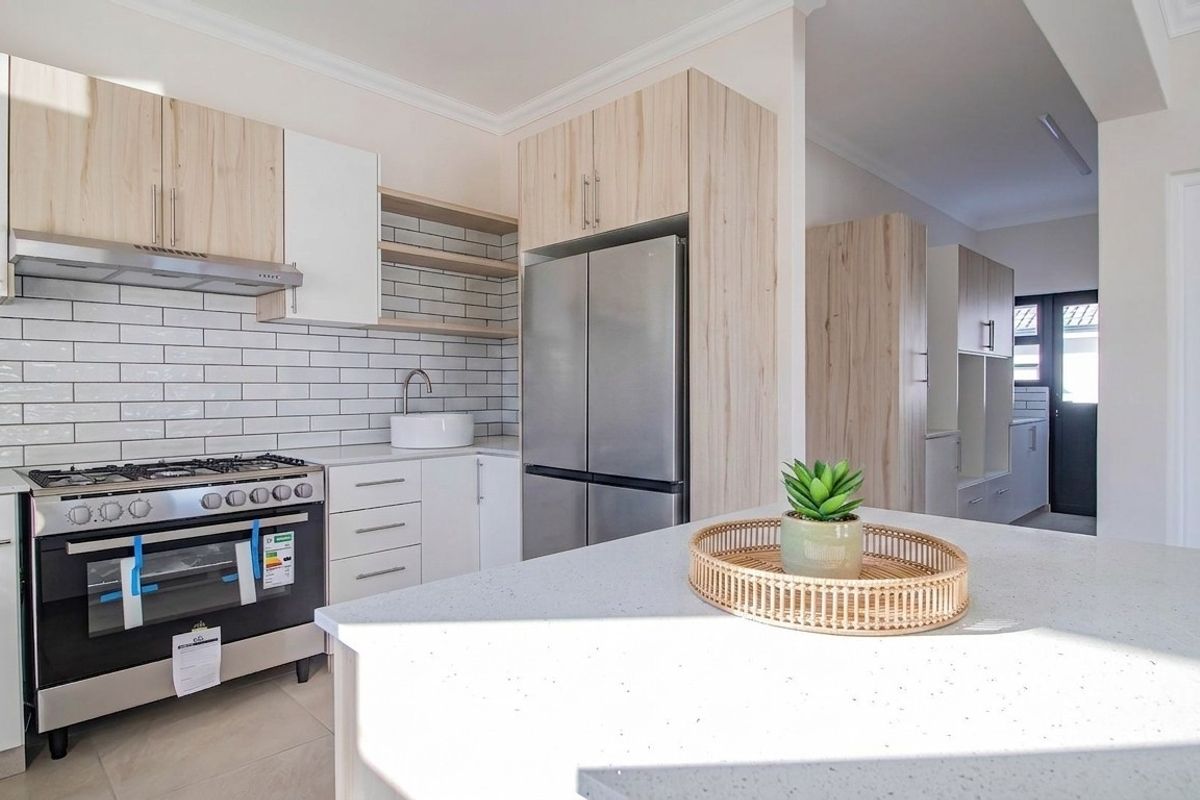 Modern kitchen featuring light wood cabinetry, stone countertops, a central island, subway tile backsplash, and a stainless steel gas stove.