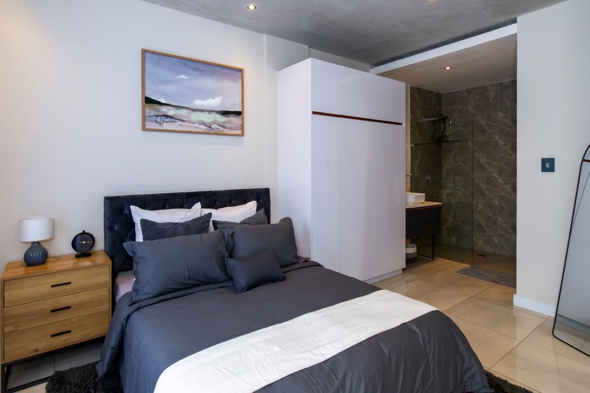 Modern bedroom featuring tiled flooring, recessed lighting, a built-in wardrobe, and an open-plan en-suite bathroom with a glass-enclosed shower.