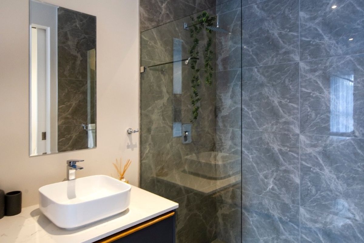Modern bathroom featuring a floating vanity with vessel sink, walk-in shower with glass screen, and elegant marble-look wall tiling.