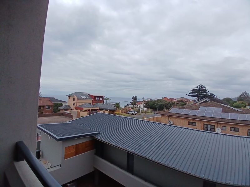 Elevated view overlooking the surrounding residential neighbourhood and rooftops with a glimpse of the ocean in the distance.