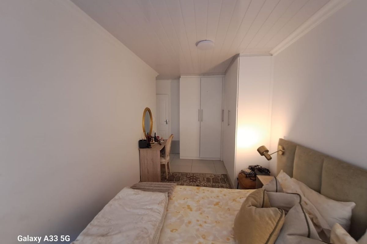 A well-maintained bedroom featuring built-in cupboards, a tongue-and-groove ceiling, and tiled flooring.