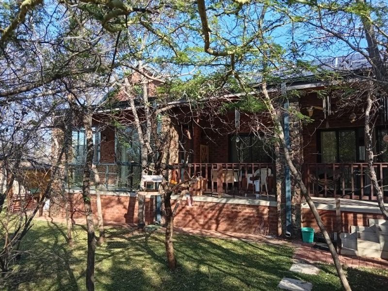 Rear view of a retirement village unit featuring a brick and stone facade, a covered patio with timber balustrades, and integrated solar panels.
