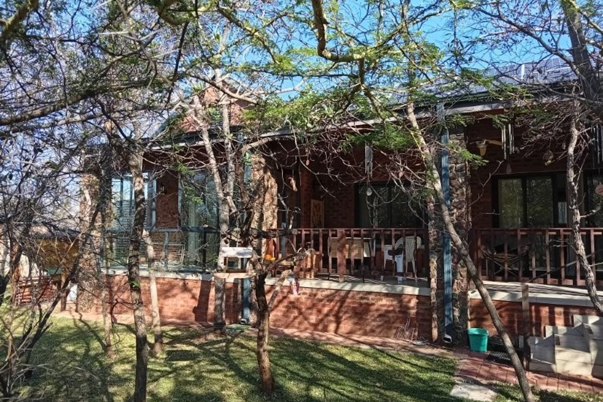Rear view of a retirement village unit featuring a brick and stone facade, a covered patio with timber balustrades, and integrated solar panels.