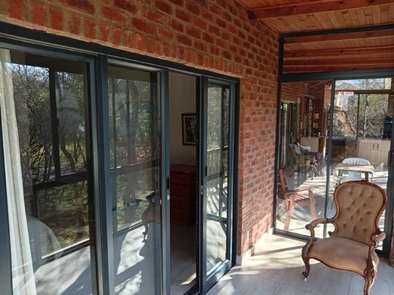 A covered patio area featuring exposed brick walls, timber ceiling, and large sliding glass doors providing access to the interior living space.