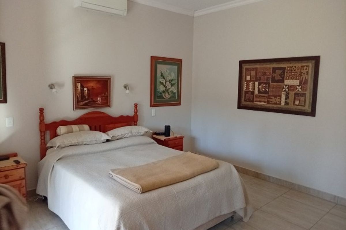 A well-maintained bedroom featuring tiled flooring, recessed lighting, and a wall-mounted split-system air conditioning unit.