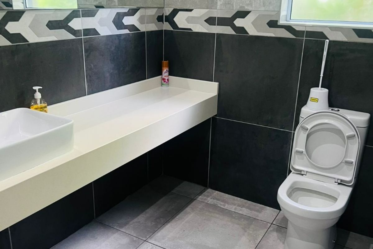 Modern bathroom featuring a wall-mounted vanity with a vessel sink, large mirror, and contemporary grey tiled walls and flooring.