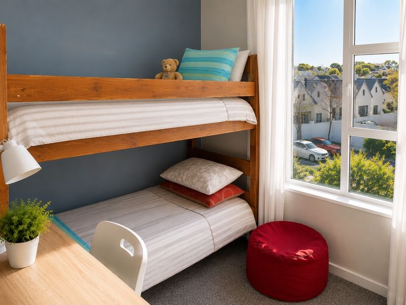 A bright bedroom featuring a large window with natural light and neutral carpeted flooring.