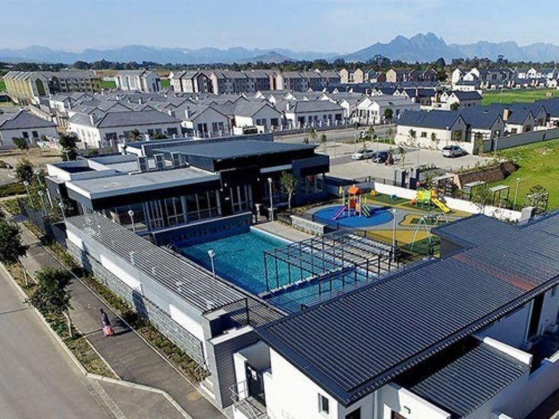 Aerial view of a modern residential complex featuring a communal swimming pool, playground area, and well-maintained surrounding infrastructure.