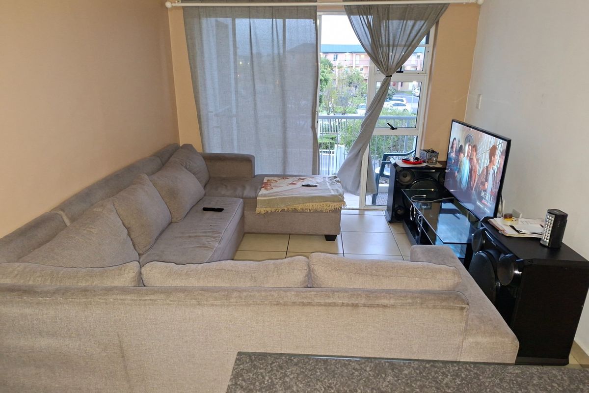 A living room featuring tiled flooring and a sliding glass door providing access to an outdoor balcony area.