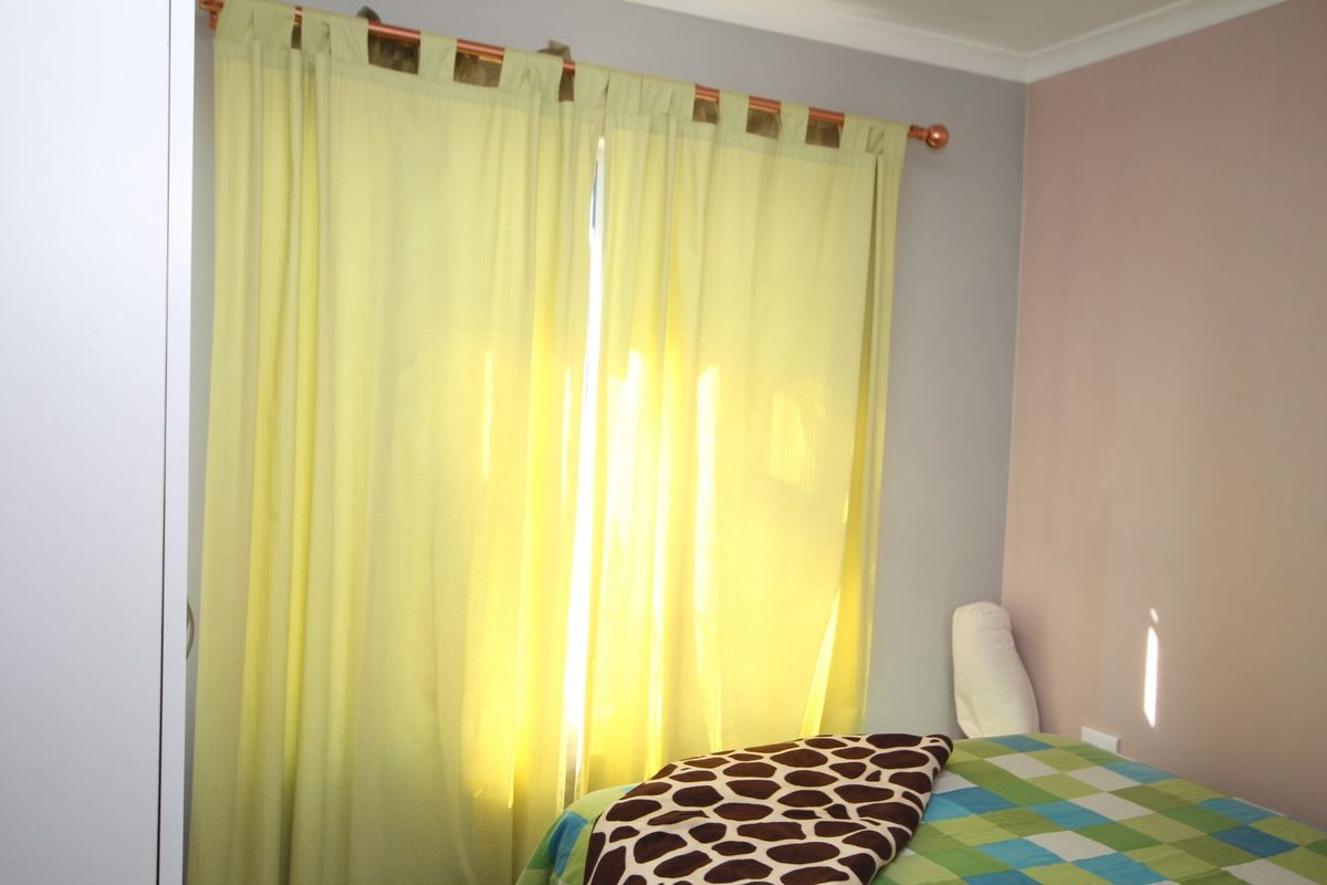 A bedroom featuring a built-in wardrobe and a window dressed with a curtain rod.