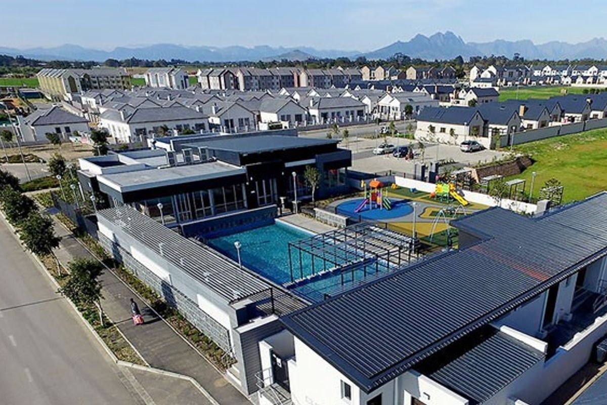 Aerial view of a modern residential estate featuring a communal swimming pool, children's playground, and well-maintained infrastructure within a secure complex.