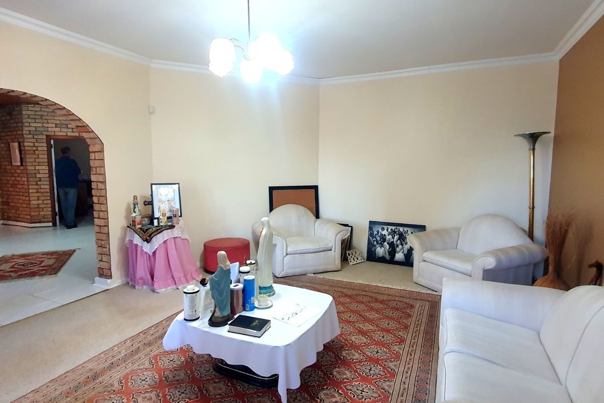 A spacious living room featuring a distinctive brick archway leading to an adjacent area, neutral wall tones, and crown molding.