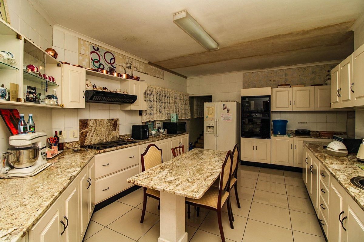 A dated kitchen featuring granite countertops, built-in oven, and tiled flooring, offering significant potential for modernization and renovation.