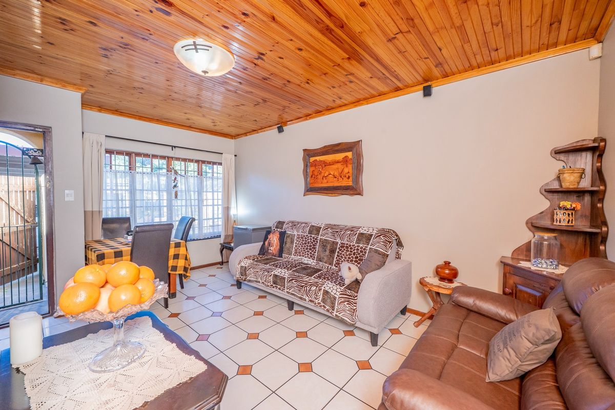 A living room featuring a timber tongue and groove ceiling, ceramic tiled flooring, and a sliding glass door leading to an outdoor area.