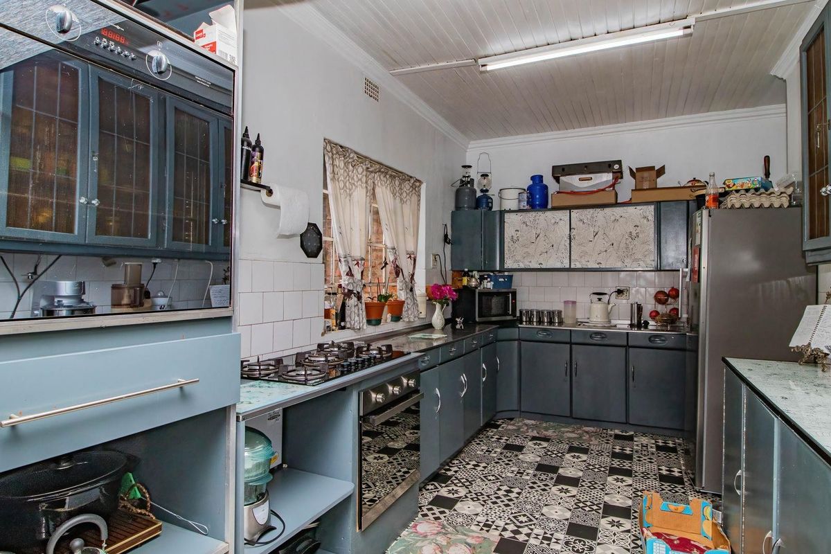 A functional kitchen featuring dark cabinetry, built-in oven and gas hob, tiled backsplash, and patterned floor tiles.