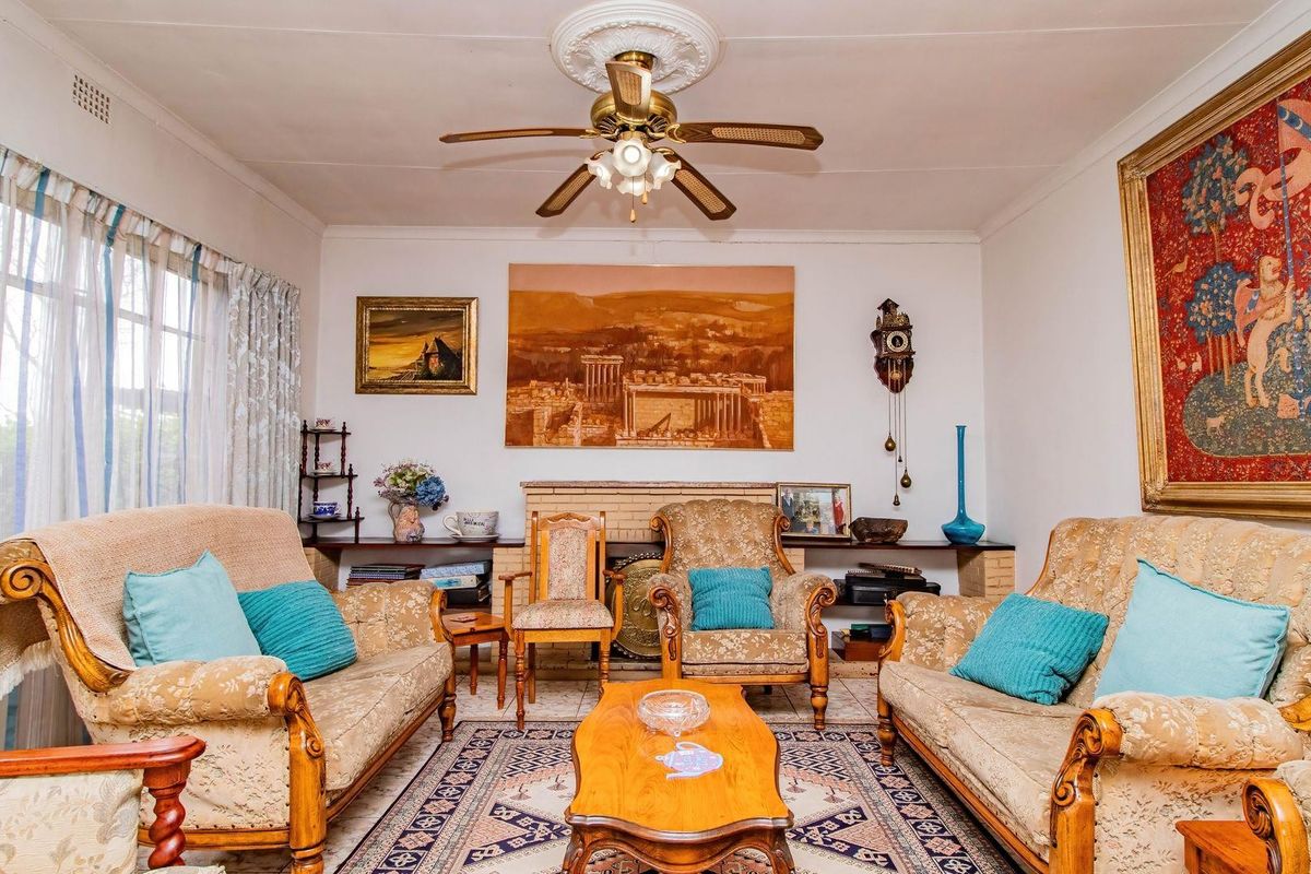 A traditional living room featuring a brick fireplace, ceiling fan, and tiled flooring, offering a classic and comfortable living space.