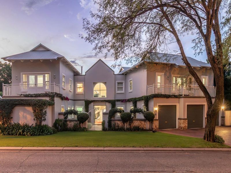 A beautifully maintained double-story residence featuring a double garage, upper-level balconies, stone accents, and a manicured front garden.