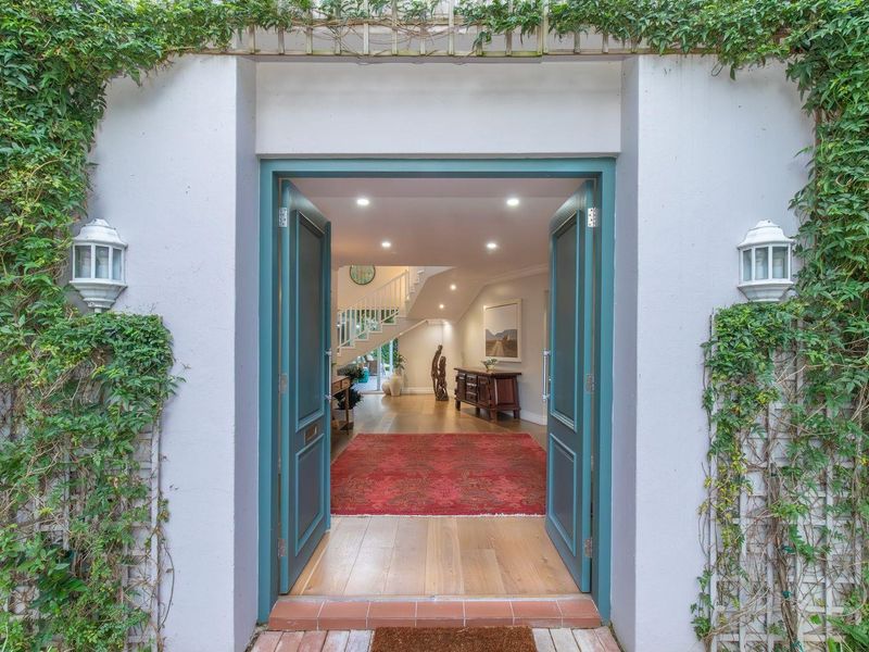 Inviting front entrance featuring double doors, hardwood flooring, and a view into the bright, open-plan interior with a staircase.