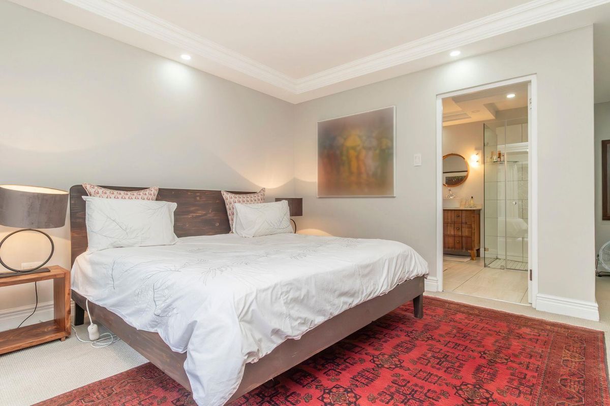 Spacious bedroom featuring crown molding, recessed lighting, and an adjoining en-suite bathroom with a modern glass shower enclosure.