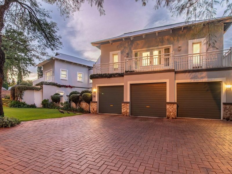 A well-maintained double-story residence featuring a triple garage, paved driveway, and an upper-level balcony with stone-clad accents.