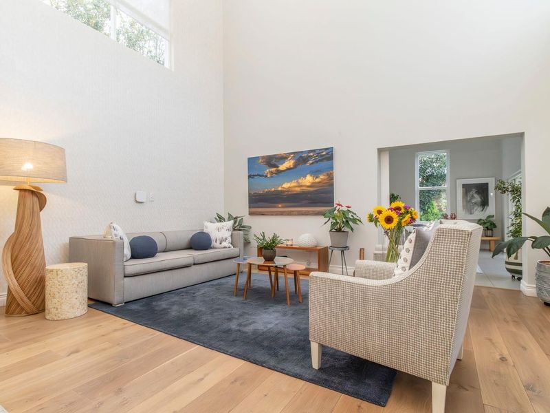 Spacious living room featuring high double-volume ceilings, clerestory windows for natural light, and warm hardwood flooring.