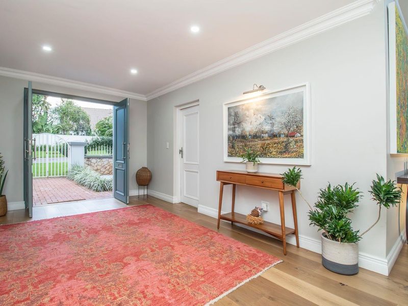 A bright and welcoming entrance hall featuring hardwood flooring, crown molding, and recessed lighting, leading directly to the front exterior.