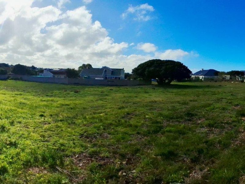 A wide panoramic view of a vacant residential plot featuring established boundary fencing and mature trees, offering a clear space for future development.