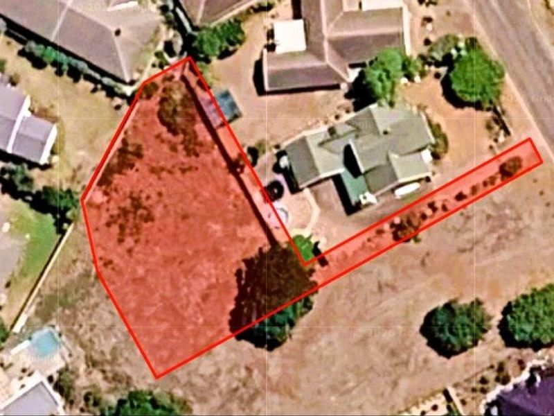 An aerial view of a vacant residential plot highlighting the property boundaries and access driveway within an established neighborhood.