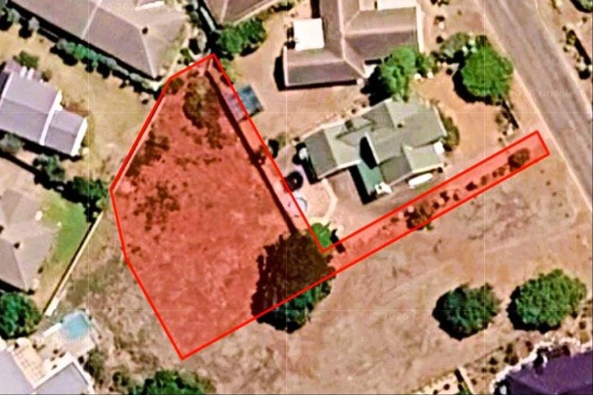 An aerial view of a vacant residential plot highlighting the property boundaries and access driveway within an established neighborhood.