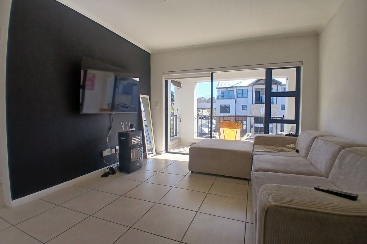 A living room featuring a dark accent wall, tiled flooring, and large sliding glass doors that provide access to a private balcony.