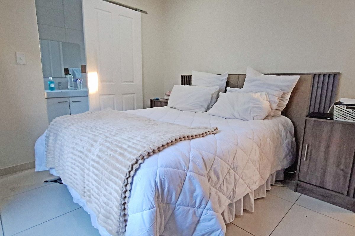 A bedroom featuring tiled flooring and an en-suite bathroom with a vanity, accessible via a sliding door.