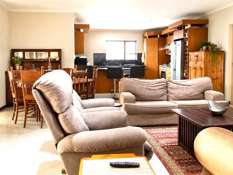 Spacious open-plan living area featuring a functional kitchen with built-in cabinetry and tiled flooring, seamlessly connecting to the dining and lounge spaces.