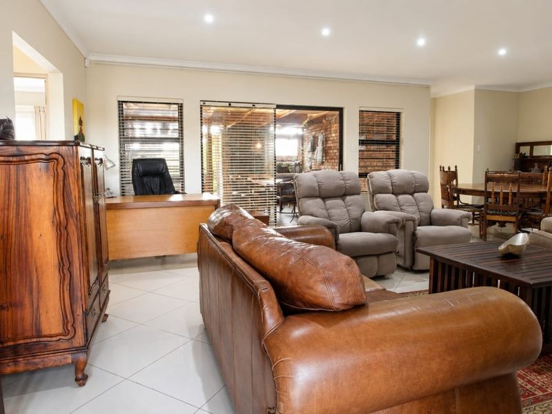 Spacious open-plan living and dining area featuring tiled flooring, recessed downlighting, and large sliding glass doors leading to an outdoor space.