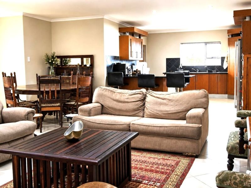 Spacious open-plan living and dining area featuring a functional kitchen with a breakfast bar, tiled flooring, and neutral wall finishes.