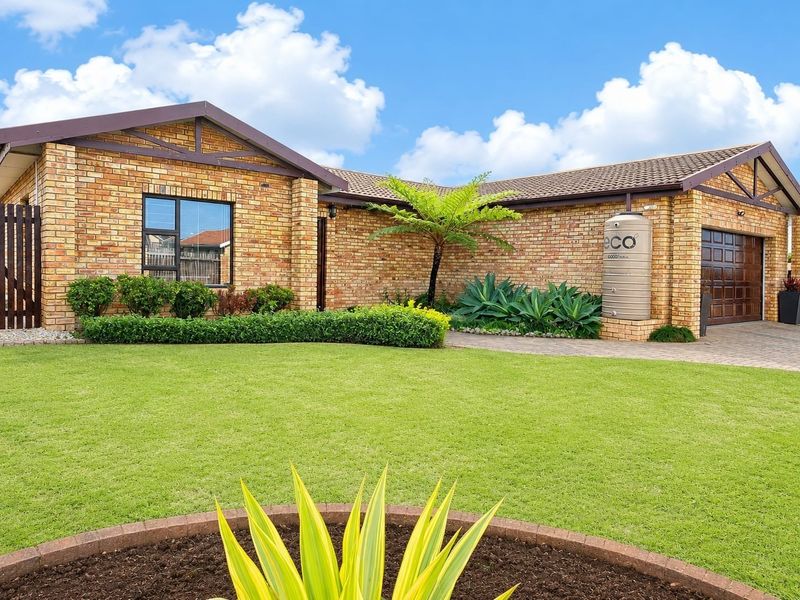 Well-maintained face brick house featuring a neat front garden, paved driveway, integrated garage, and a water storage tank.