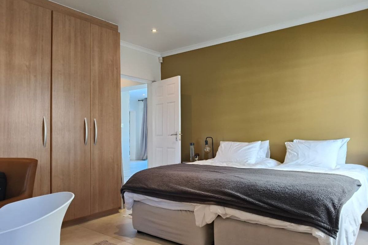 A well-maintained bedroom featuring built-in wooden wardrobes, tiled flooring, and recessed ceiling lighting, offering a clean and functional living space.
