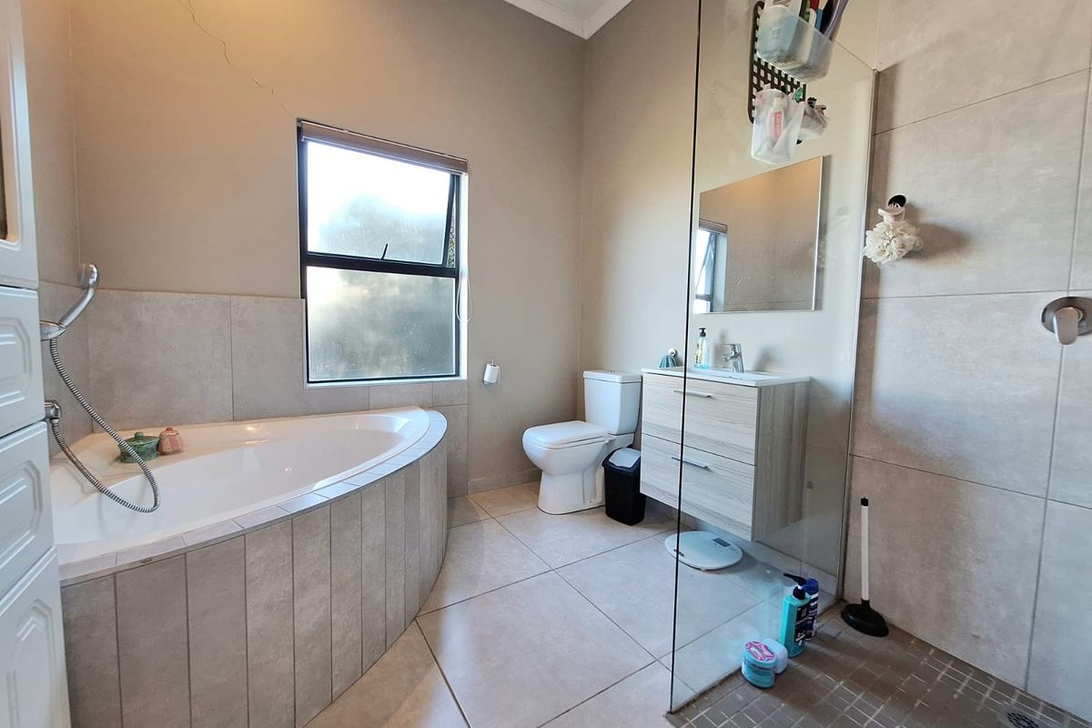 Modern bathroom featuring a corner bathtub, a glass-enclosed walk-in shower, a wall-mounted vanity, and tiled flooring.