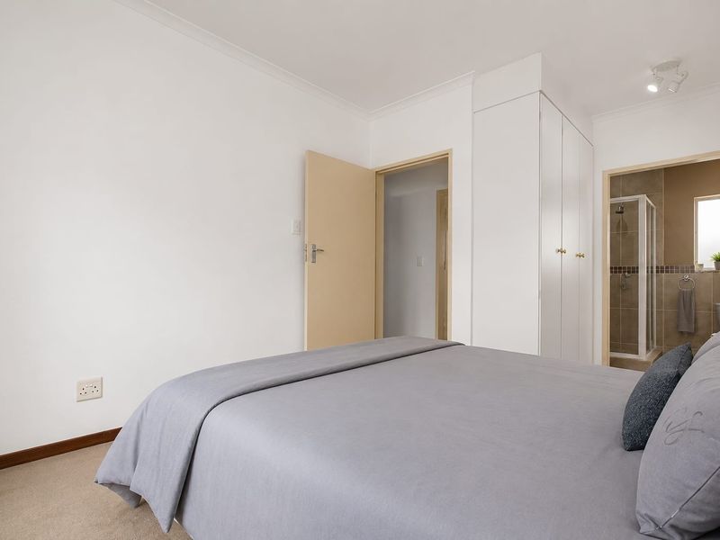 A bedroom featuring built-in cupboards and an en-suite bathroom with a shower.
