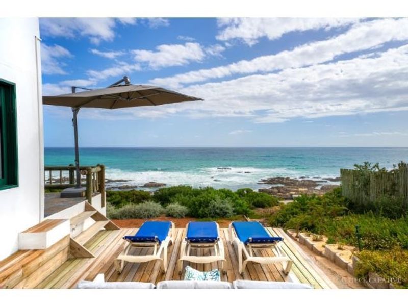 A scenic outdoor patio deck featuring timber decking and direct ocean views, providing a tranquil space for relaxation overlooking the coastline.