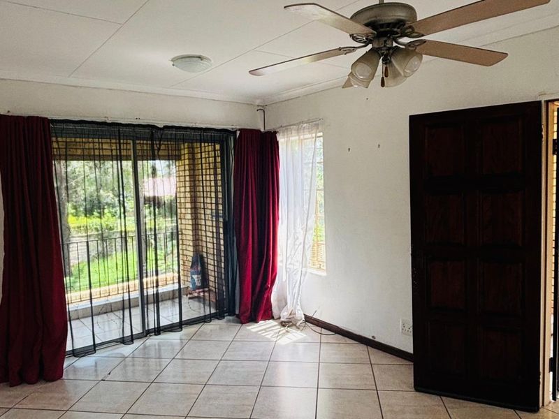 A spacious living area featuring tiled flooring, a ceiling fan, and sliding glass doors that open onto an outdoor patio space.