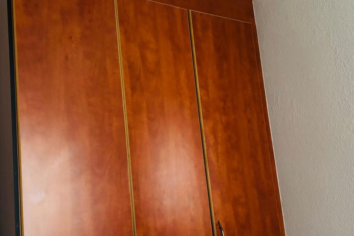 A bedroom featuring built-in wooden cabinetry with integrated handles, providing ample storage space.