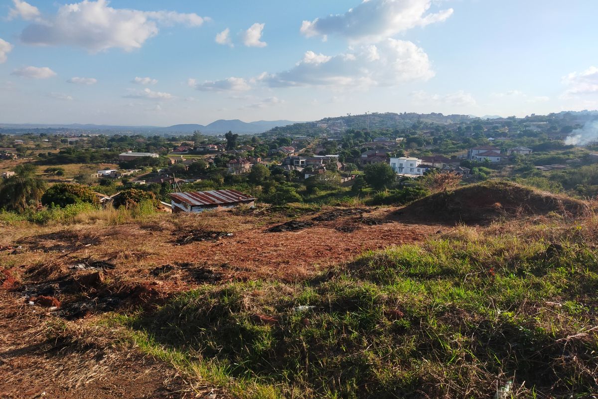 A wide-angle view overlooking a residential neighbourhood from an elevated, undeveloped plot of land.