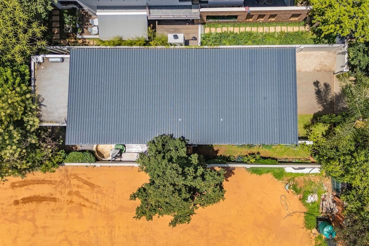Aerial view of the property showing the main roof structure, surrounding garden areas, and paved driveway access.