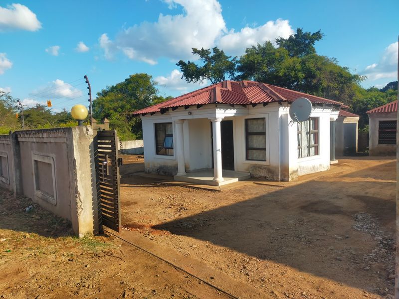 Front exterior view of a commercial property featuring a metal roof, concrete columns, and a perimeter wall with electric fencing.