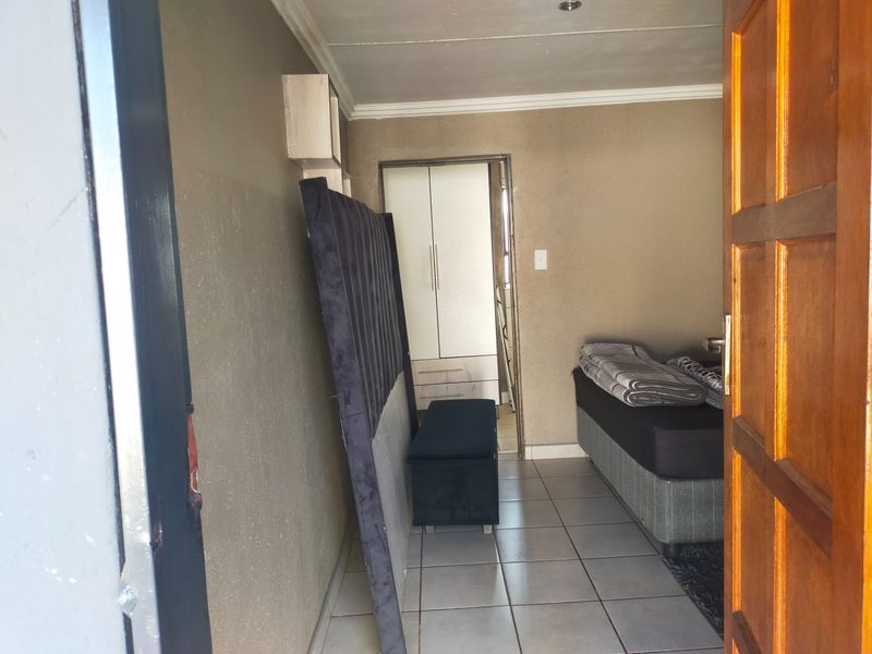 A bedroom featuring tiled flooring, a built-in wardrobe, and coved ceiling details, viewed from the entrance doorway.