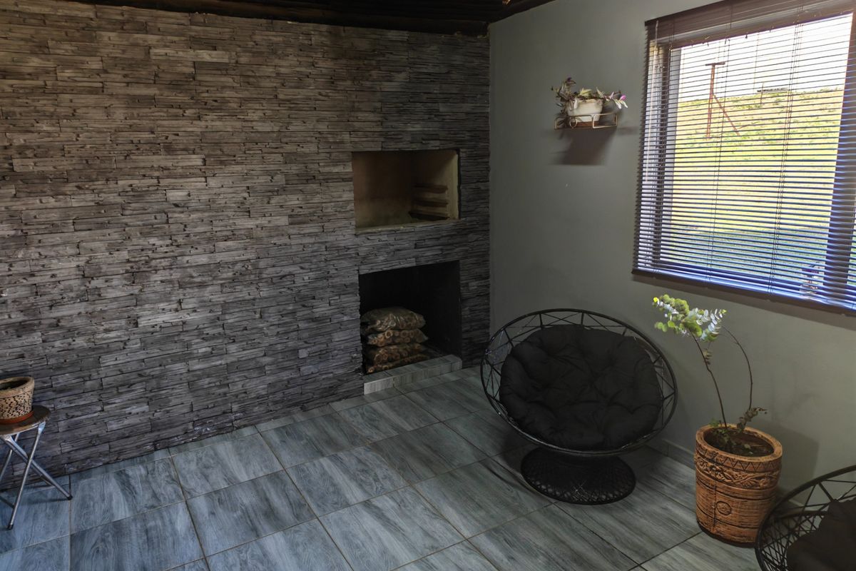 Indoor entertainment area featuring a stone-clad feature wall with a built-in fireplace and tiled flooring.