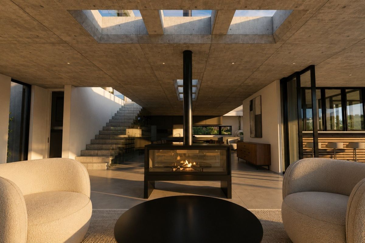 Spacious open-plan living area featuring an exposed concrete ceiling with skylights, a central modern fireplace, and a striking concrete staircase.