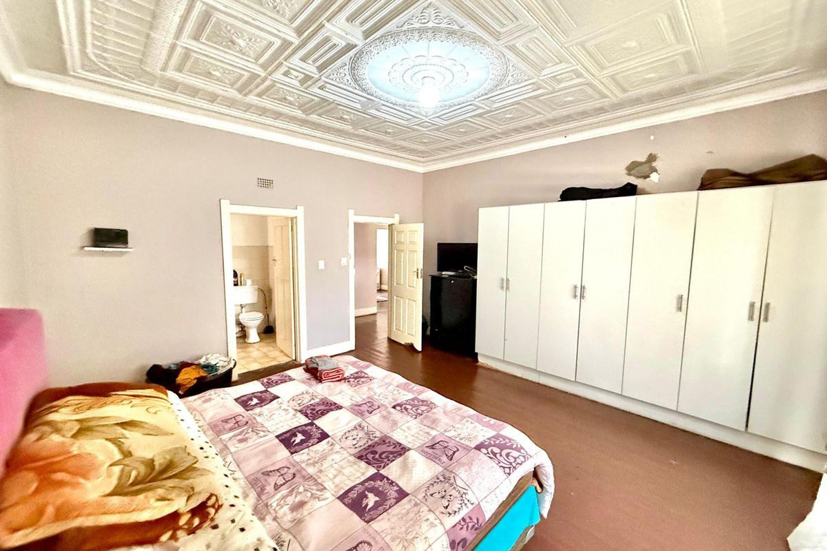 Spacious bedroom featuring a decorative pressed metal ceiling, built-in wardrobes, and an en-suite bathroom.
