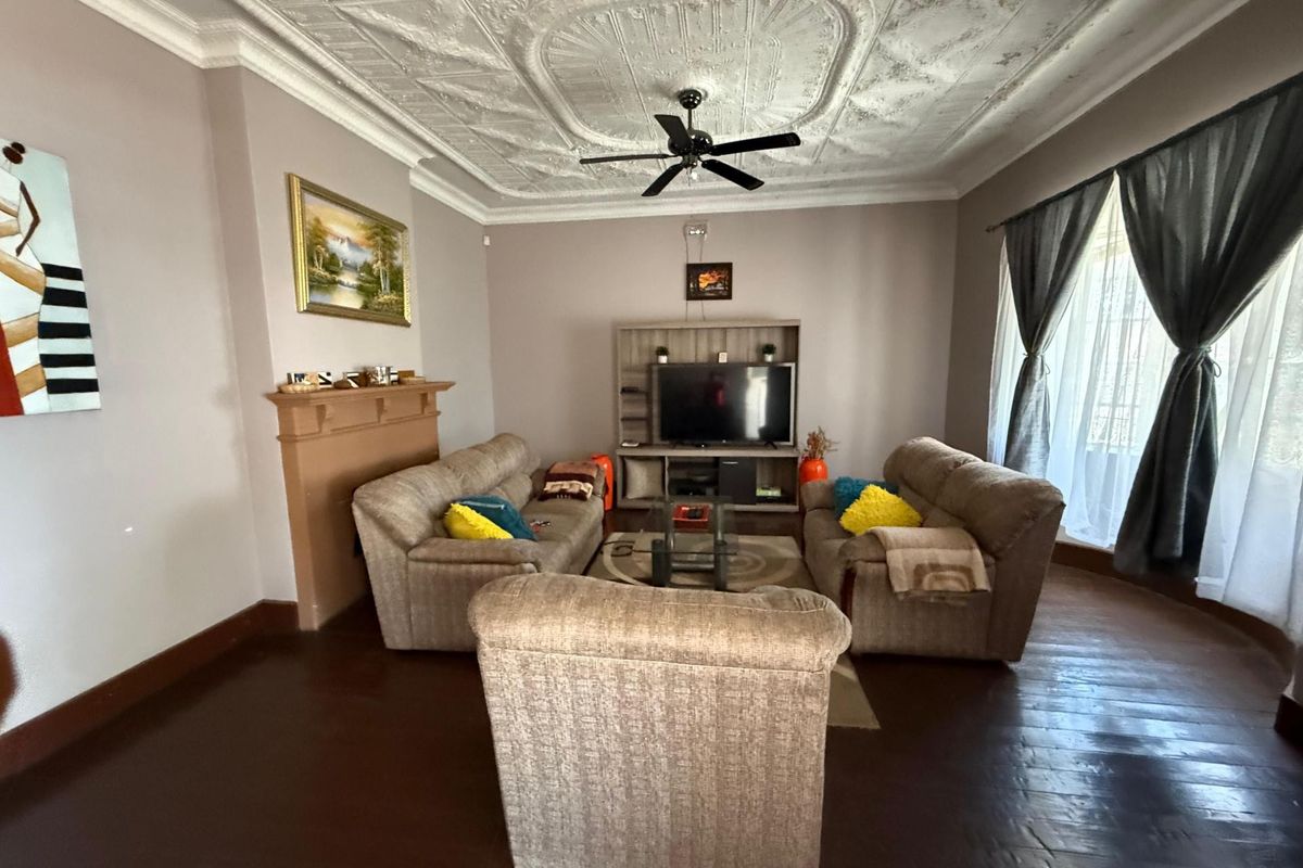 Spacious living room featuring a decorative pressed metal ceiling, ceiling fan, and a traditional fireplace mantle.
